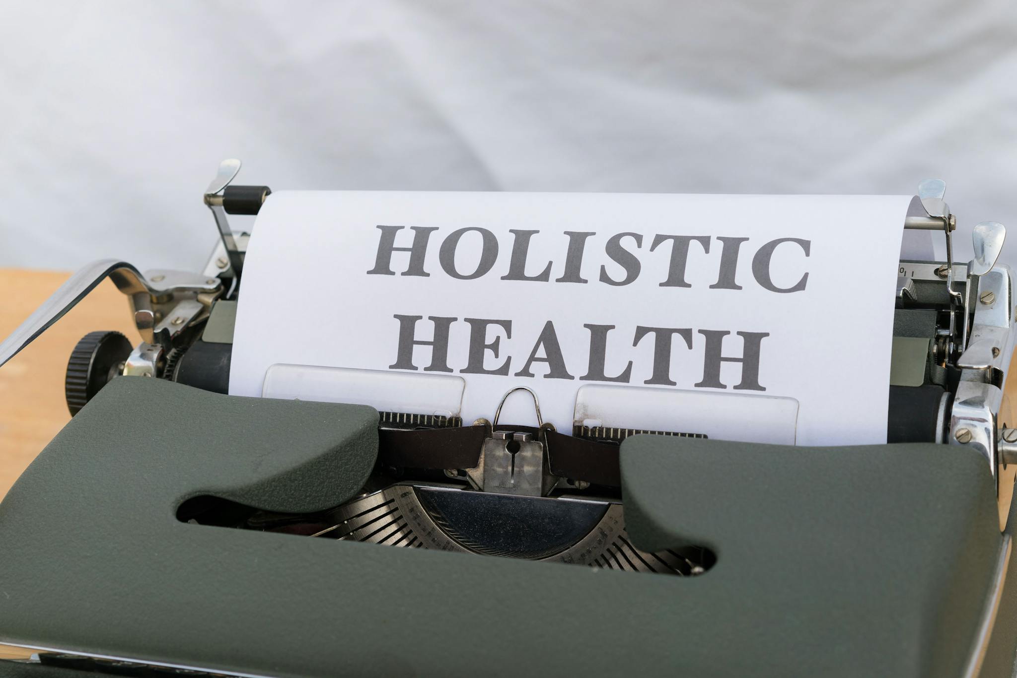 Close-up of a vintage typewriter with 'Holistic Health' typed on paper, symbolizing wellness.