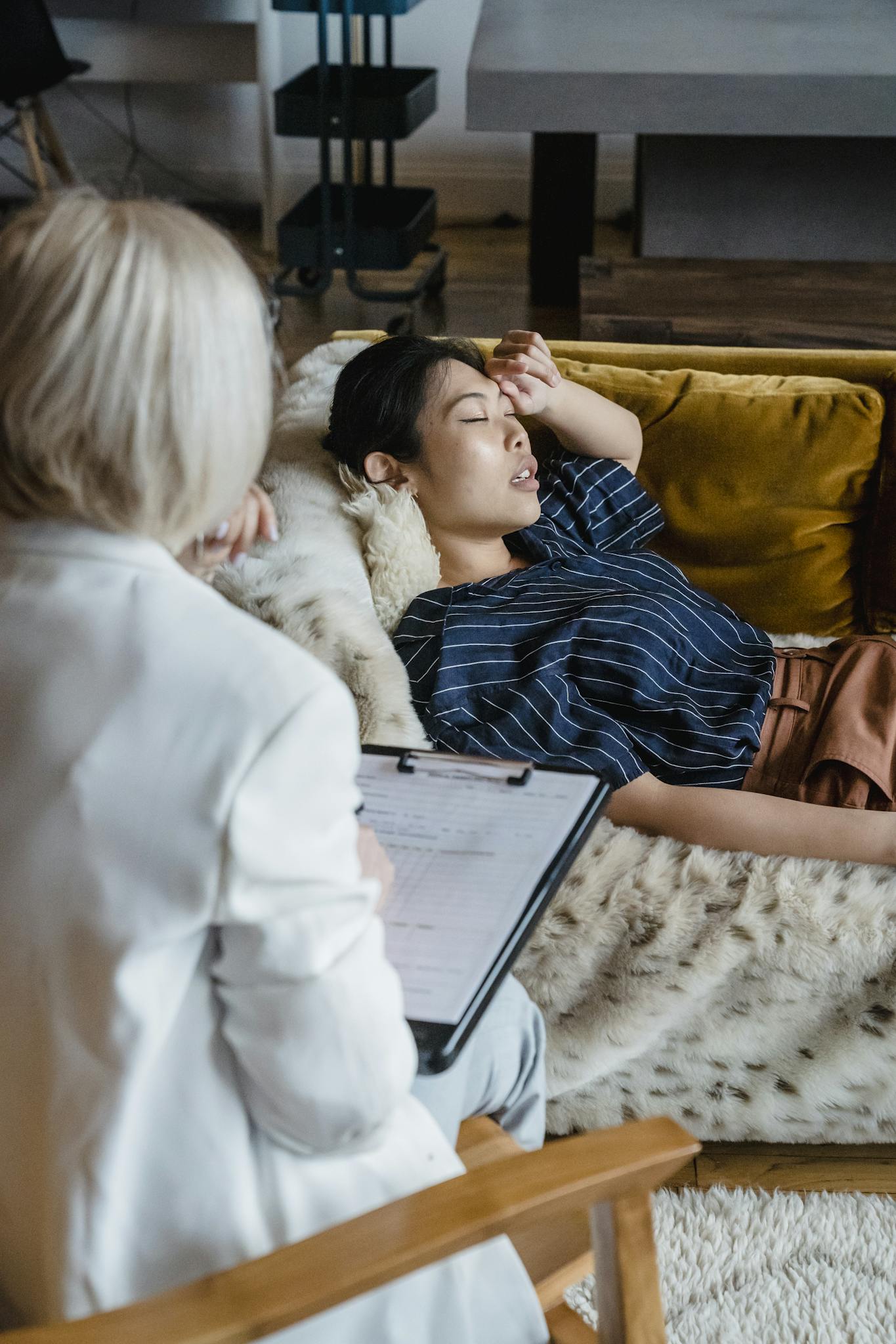 Woman in therapy session with psychologist, expressing emotions, lying on couch.